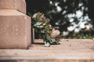 Bouquet of flowers lying on a stone ledge outdoors, with blurred trees in the background