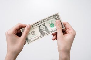 Hands holding a one-dollar bill against a white background