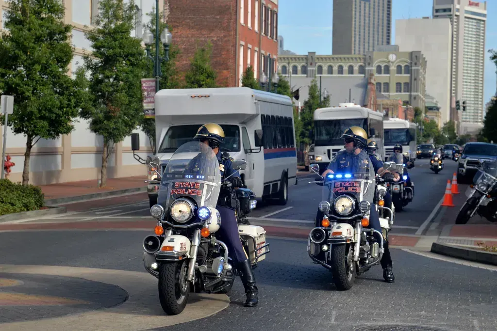 Police motorcycles escorting buses on a city street.