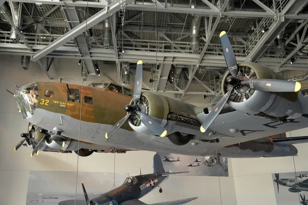 Vintage four-engine military bomber suspended in an aircraft museum, viewed from below.