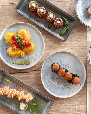 Un assortimento di antipasti serviti su un tavolo di legno, tra cui salmone, funghi e stuzzichini guarniti.
