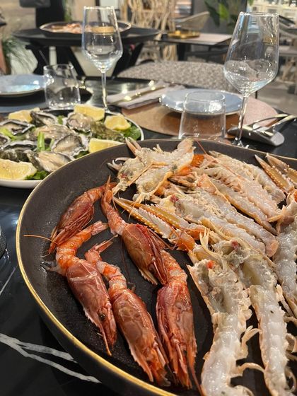 Piatto di frutti di mare con zampe di granchio e gamberi rossi su una padella nera al tavolo di un ristorante.