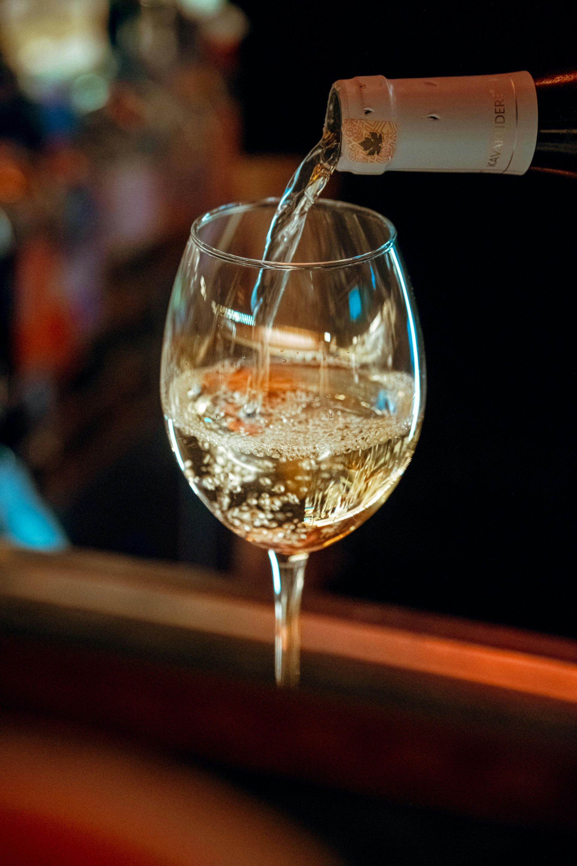Vino bianco versato in un bicchiere in un bar scarsamente illuminato