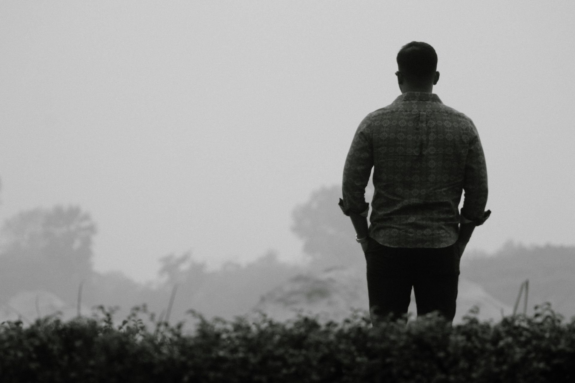 a photo of a man in siloutte looking out form a field into the distance
