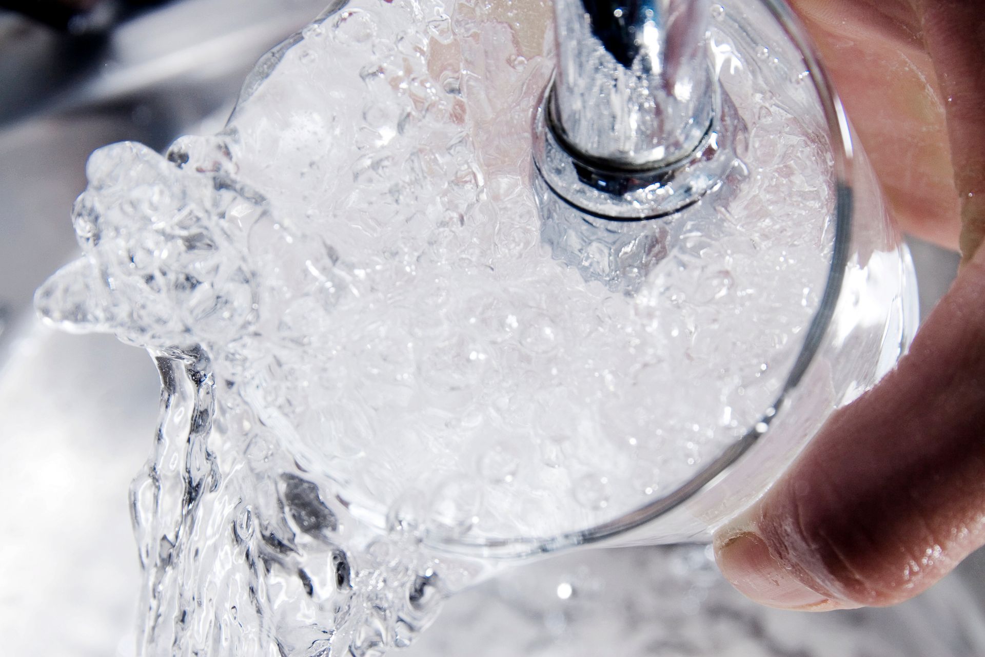 Clean water coming out of faucet onto glass.