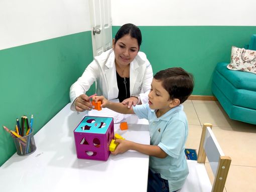 Profesional sanitario ayudando a un niño sentado en una consulta con paredes verdes