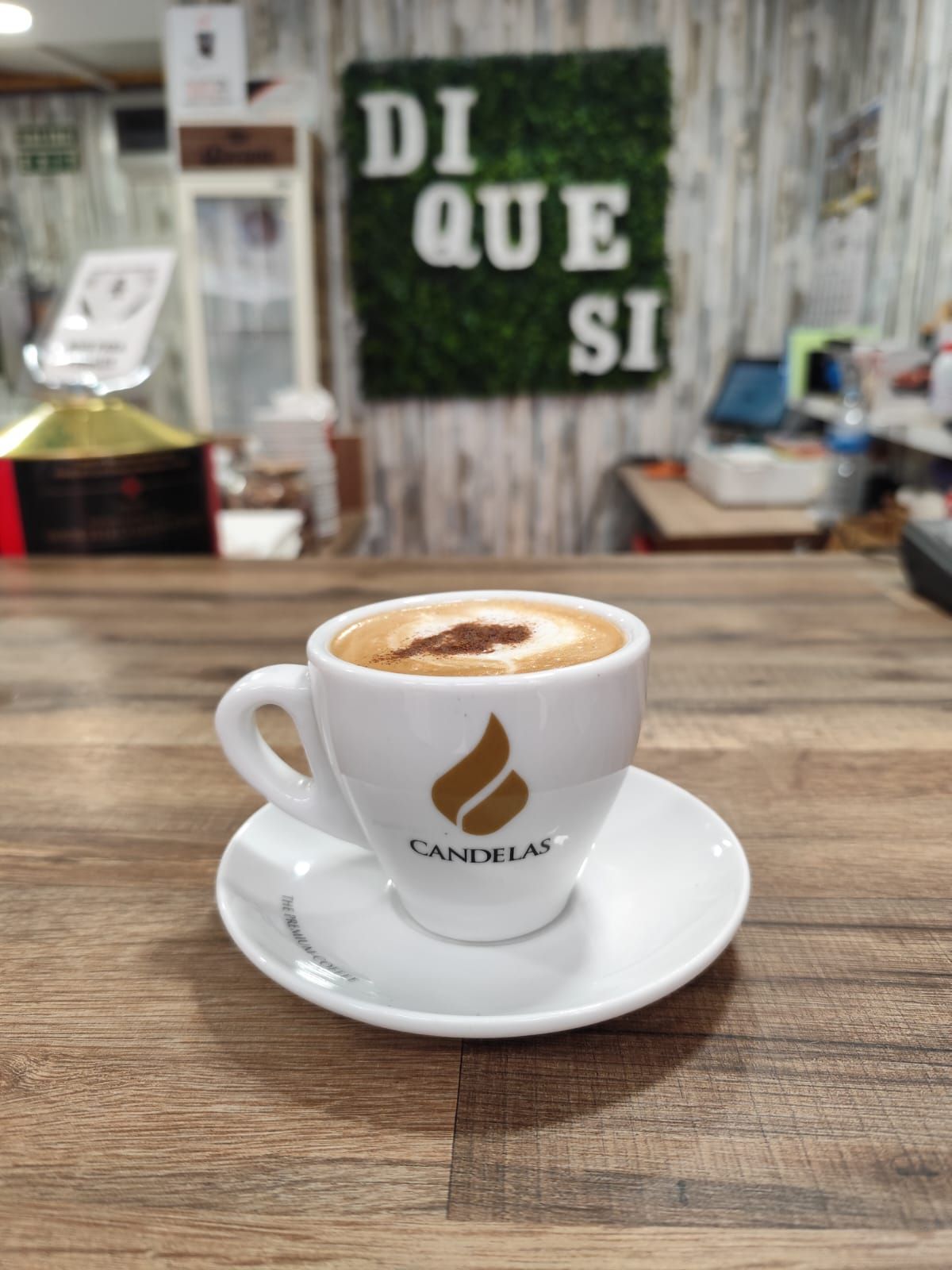 Espresso en taza blanca con platillo sobre un mostrador de madera, con
