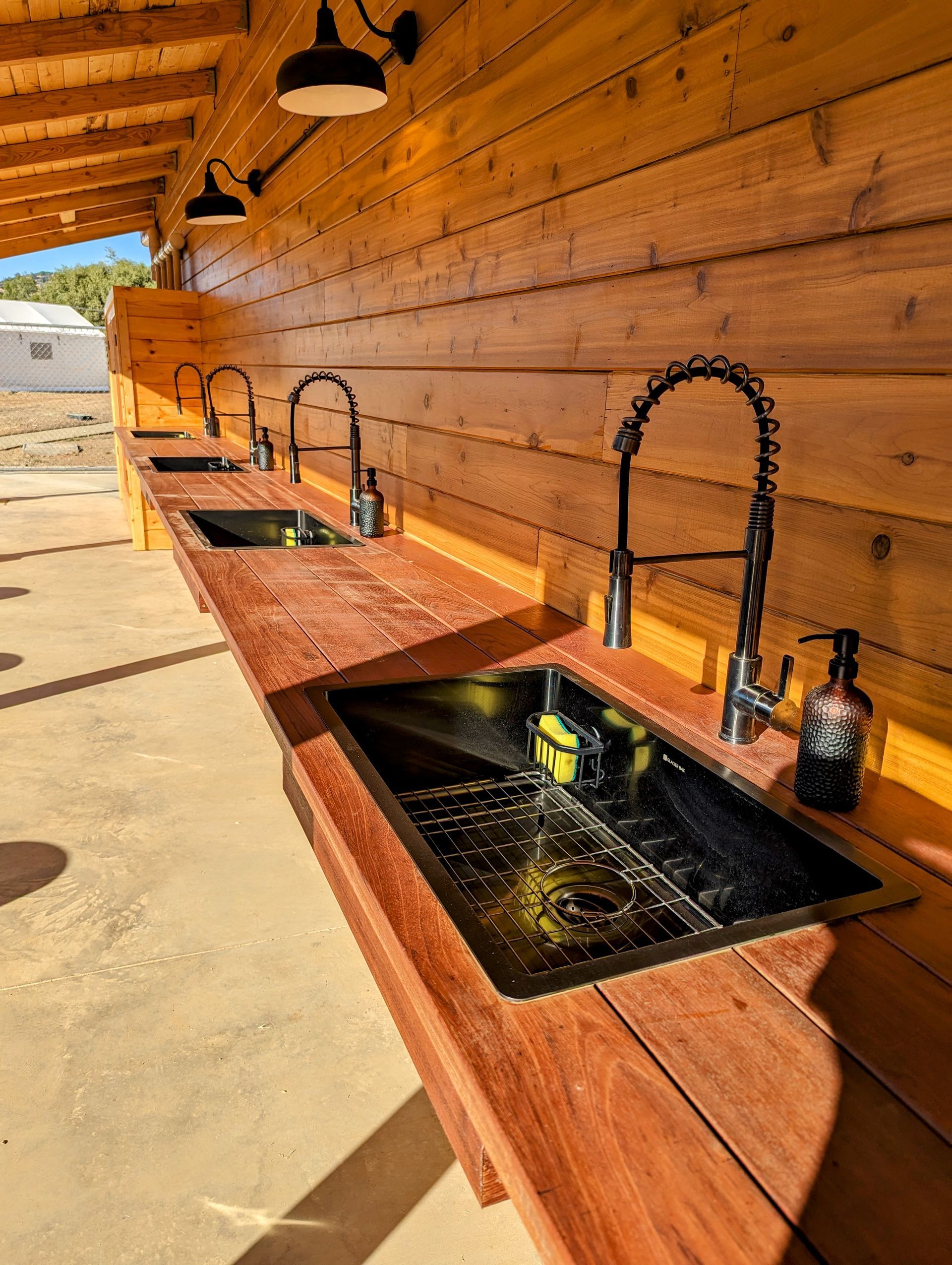 A row of sinks on a wooden counter in a kitchen.