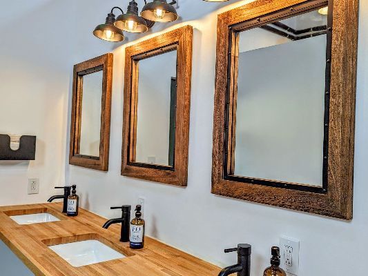 A bathroom with two sinks and three mirrors on the wall.