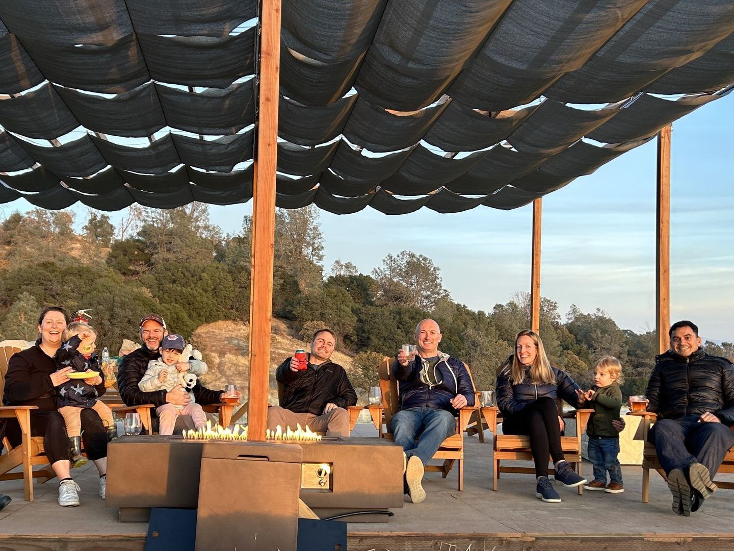 Group of people wiht kids sitting in Pergola around firepit