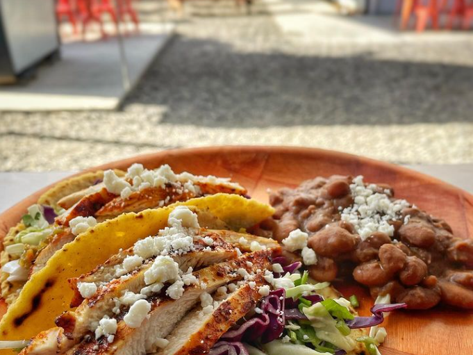 A close up of a plate of food with beans and tacos on a table.