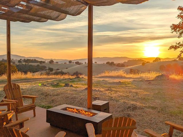 There is a fire pit on the patio with a view of the sunset.