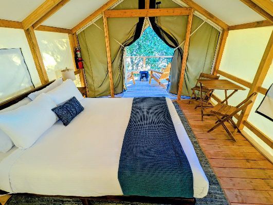 A tent with a bed and chairs inside of it
