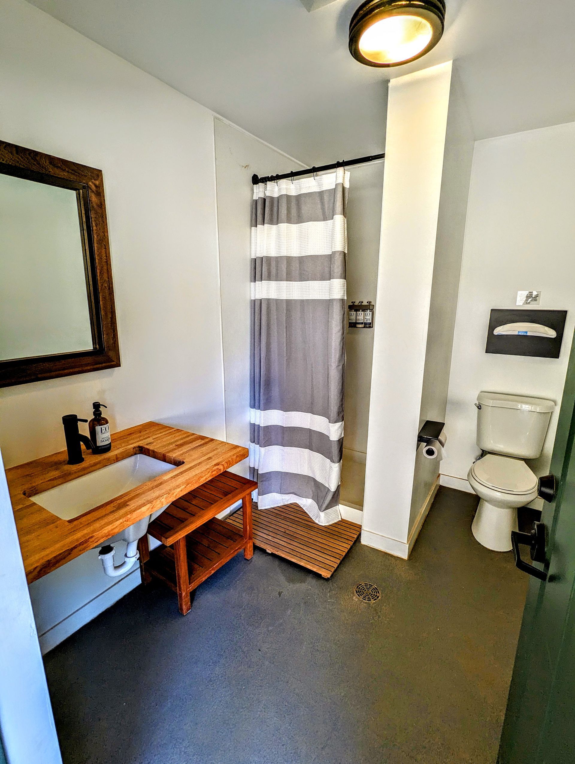 A bathroom with a sink , toilet , shower and mirror.