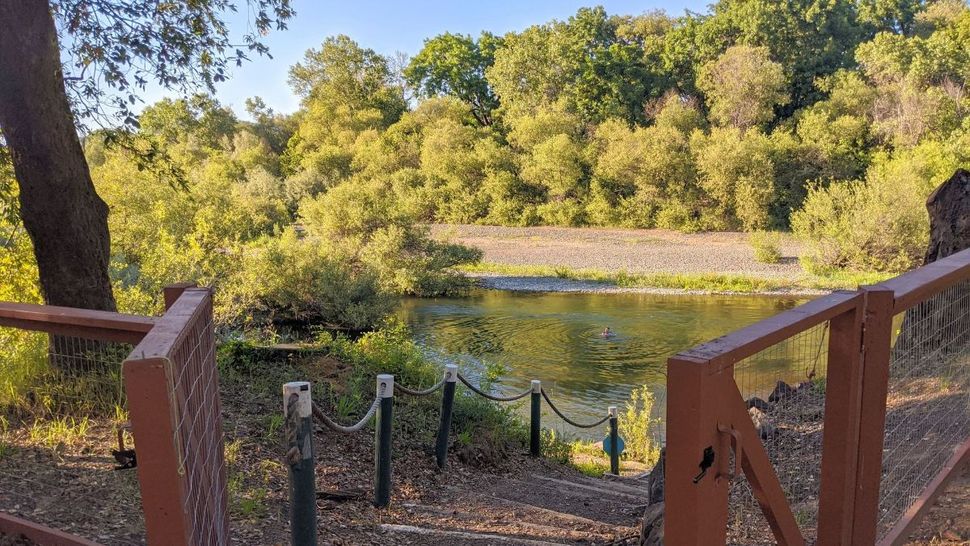 A wooden fence leading to a lake surrounded by trees.