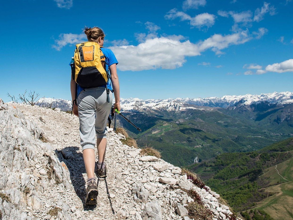A woman with a backpack is hiking up a mountain.
