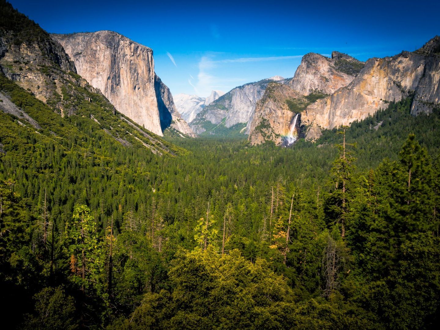 A view of a valley surrounded by mountains and trees.
