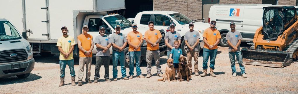 A group of men and a dog are posing for a picture in front of their trucks. Concrete cutting