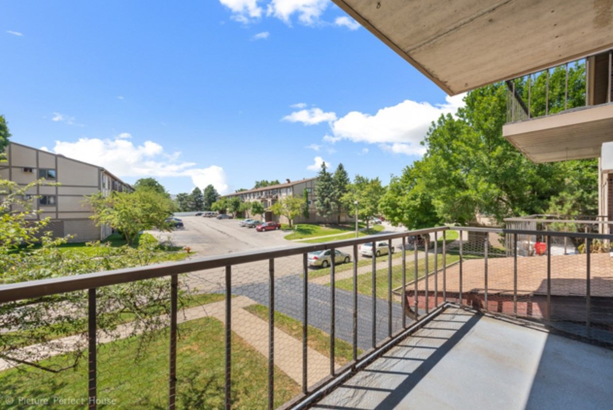 A balcony with a view of a street and trees