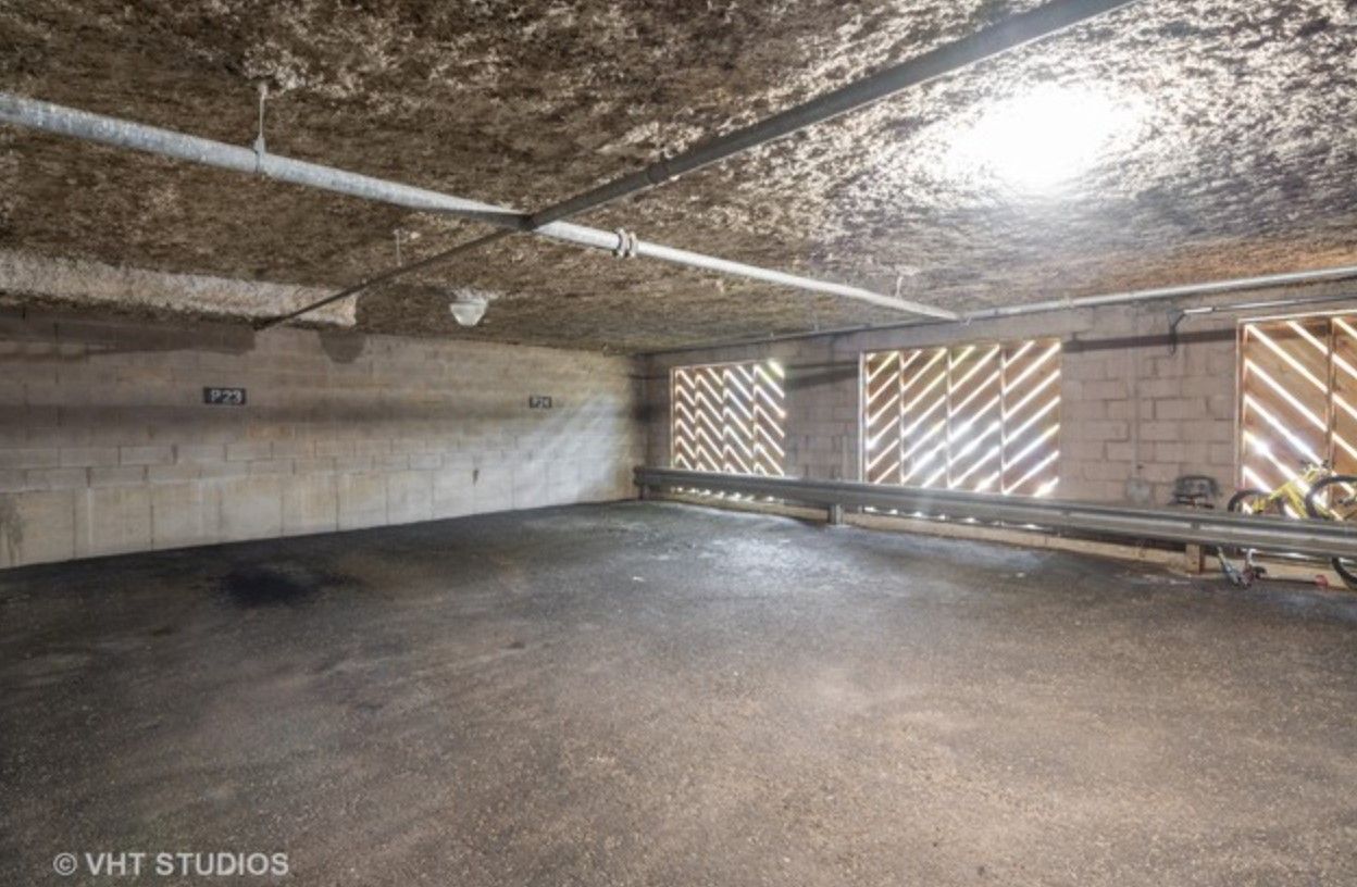 An empty parking garage with a light shining through the ceiling.