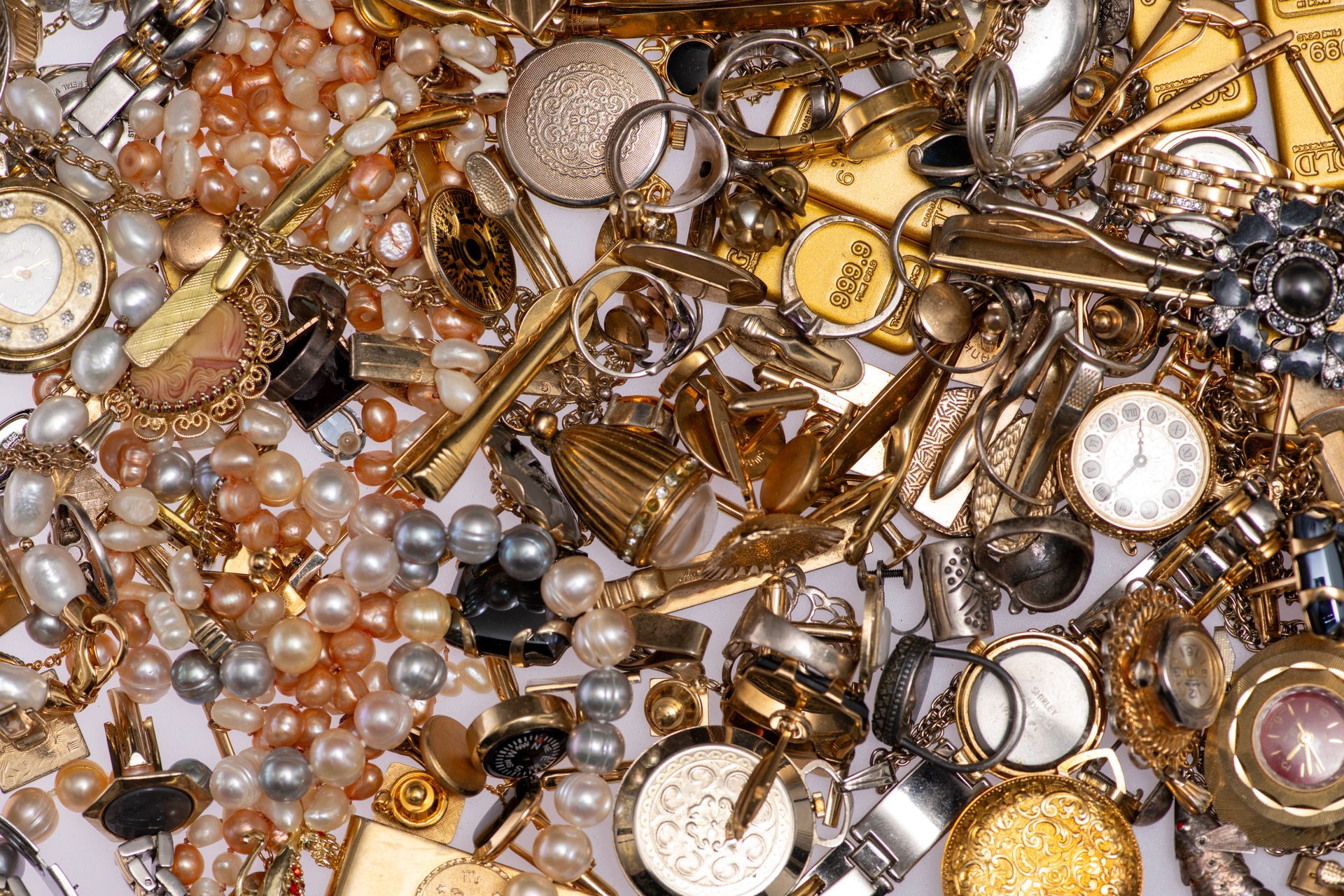 Different types of antique jewellery lie in a clutter on a white background.