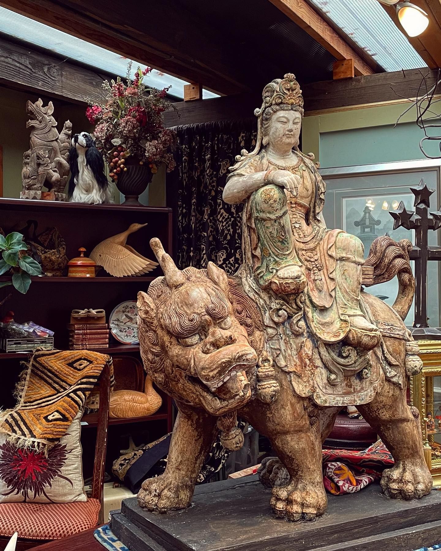 Ornate statue of a woman riding a lion in a shop filled with decorative art pieces