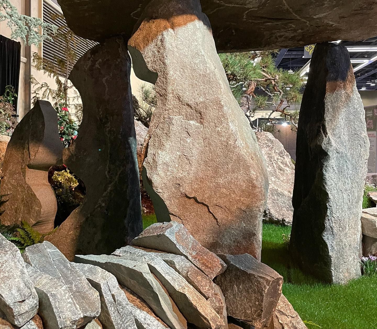 Stone sculptures and angular rock forms in a garden with grass and trees