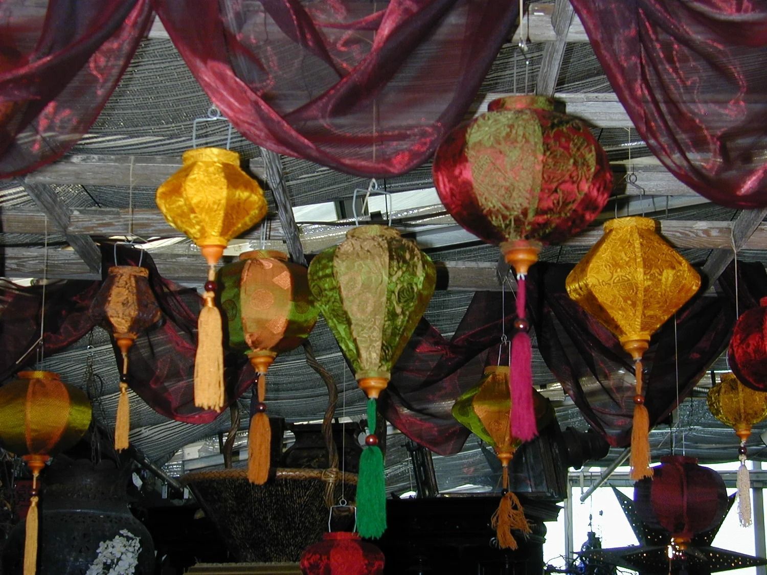 Colorful hanging lanterns and draped fabric under a decorated ceiling, likely at an indoor festival or market.