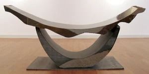 Abstract wooden sculpture with a curved top balanced on a circular base