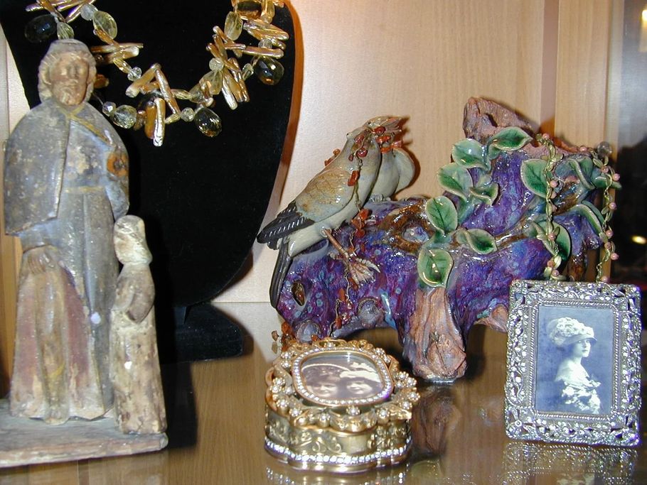 Decorative figurines and jewelry on a shelf, including a purple-green rock and small framed portrait