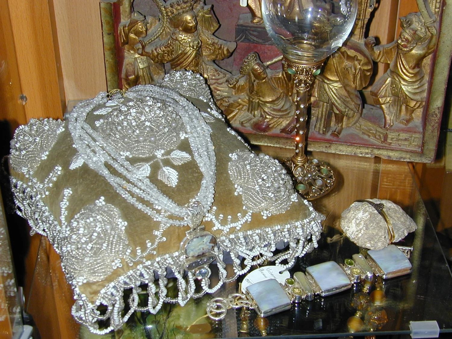 Decorative lace-covered book or box with gold trim on a shelf, beside small ornaments and framed art