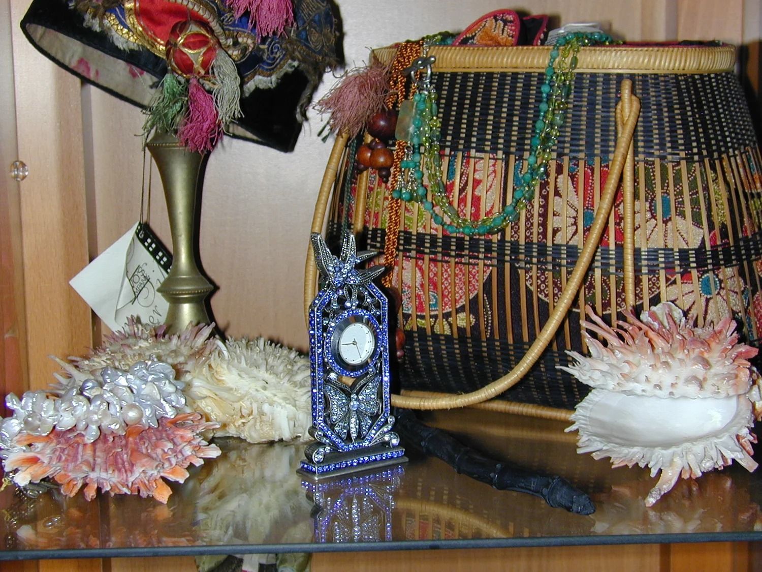 Decorative table display with colorful flowers, a clock, and a beaded lampshade on a glossy surface