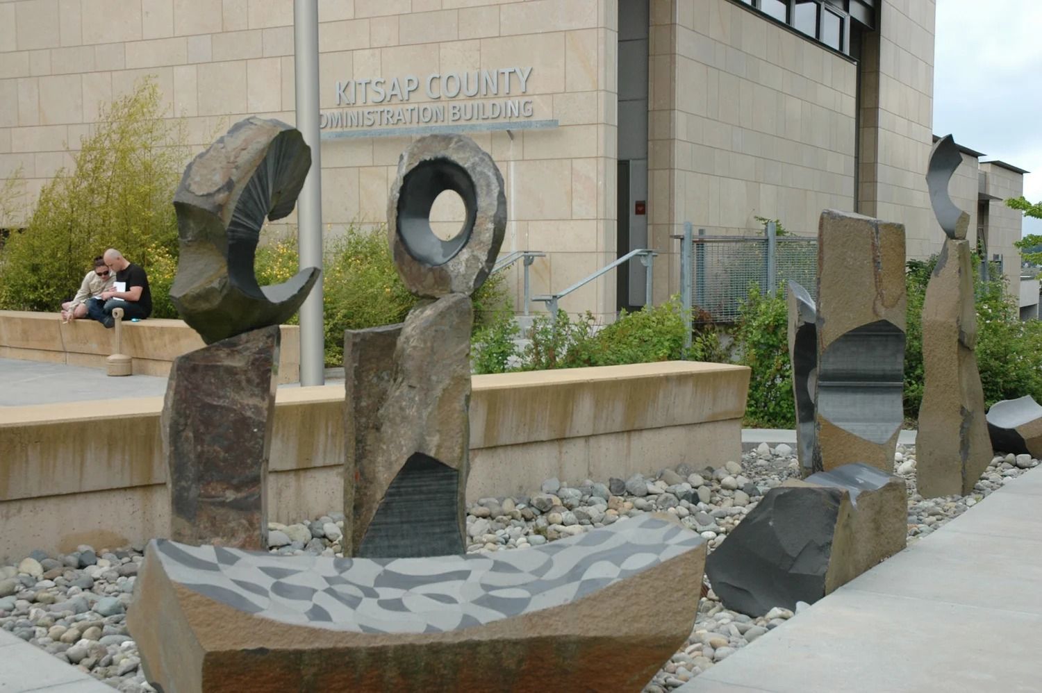 Abstract metal sculptures outside a museum building with benches and stone landscaping