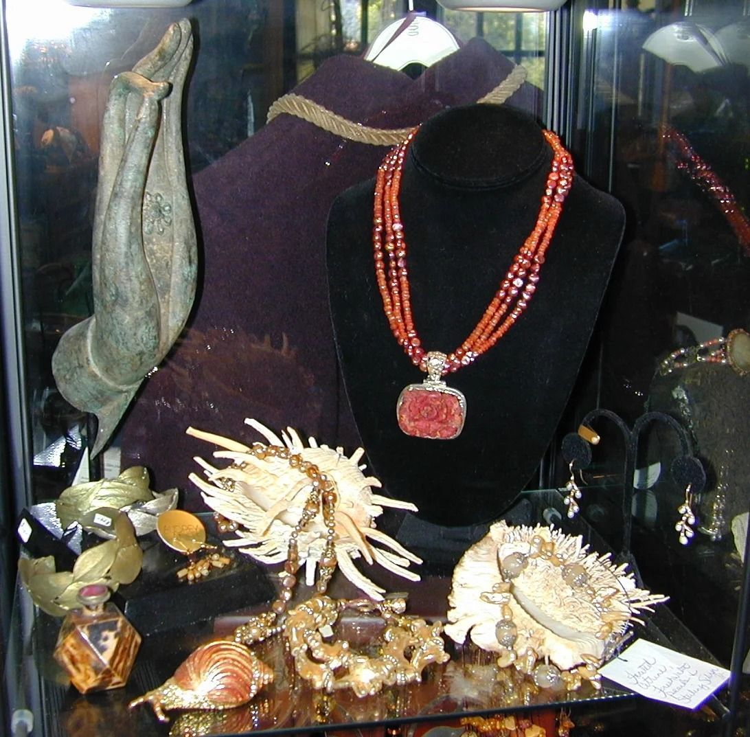Display case with ornate jewelry and shell-like decorative pieces on a black velvet bust