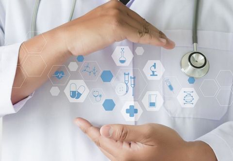A doctor with a stethoscope around his neck is holding a bunch of medical icons in his hands.
