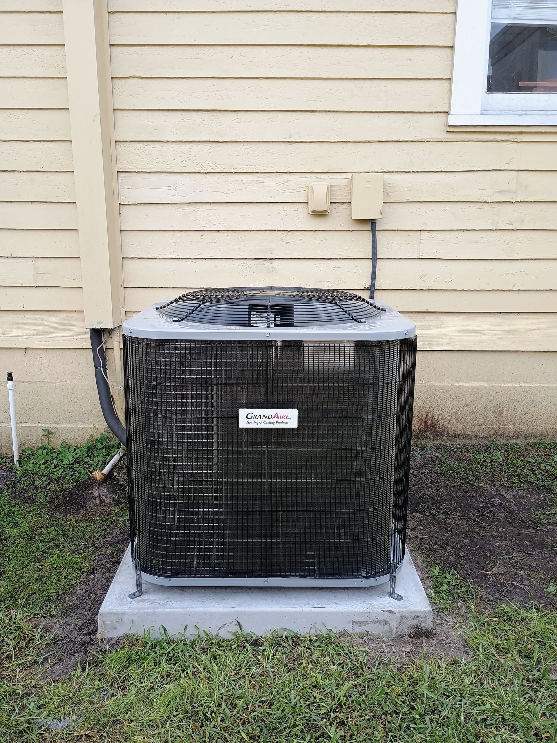Central air conditioning unit outside a light-colored house.
