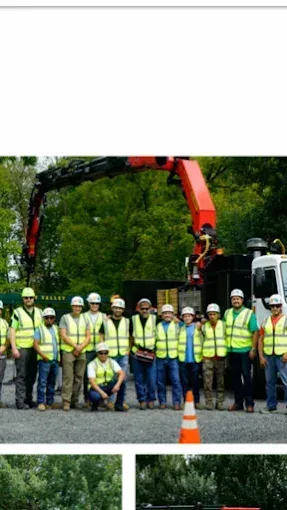 Group of workers in safety vests and helmets posing with a crane truck.