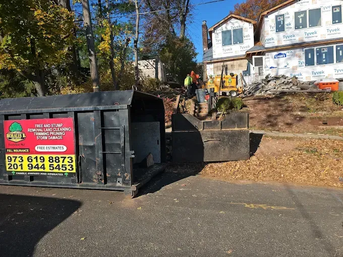 Dumpster in front of a house under construction; a tractor is moving debris.