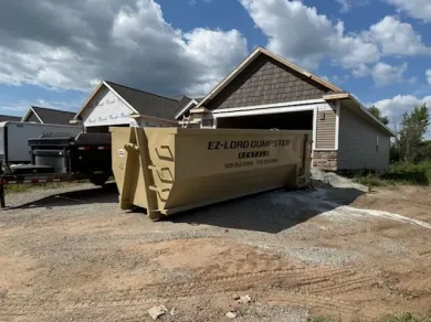 A dumpster is parked in a driveway next to a house.