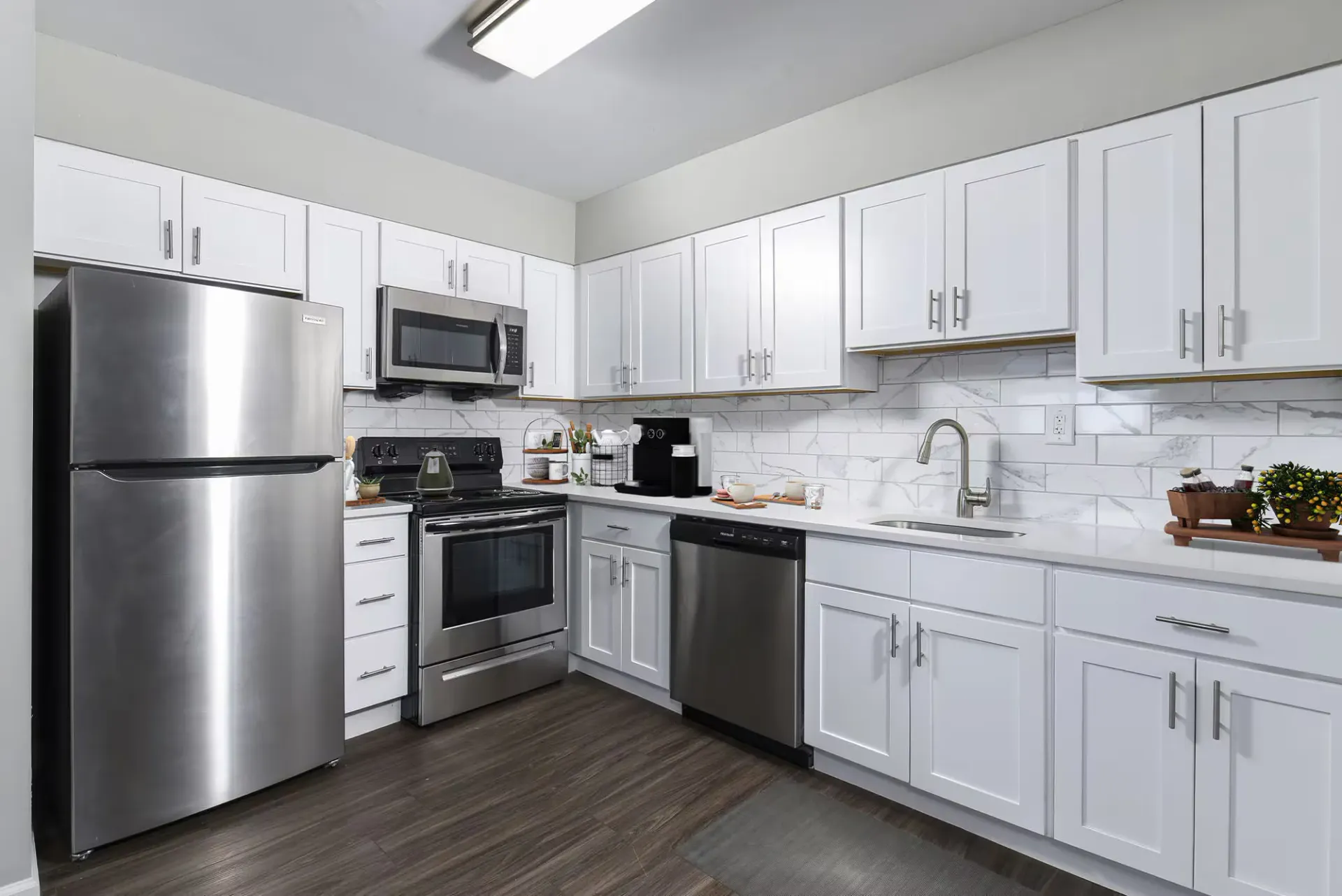 Modern kitchen with white cabinets, stainless steel appliances, and marble backsplash at The Addison, offers apartments for rent in North Wales near Gwynedd Mercy University.