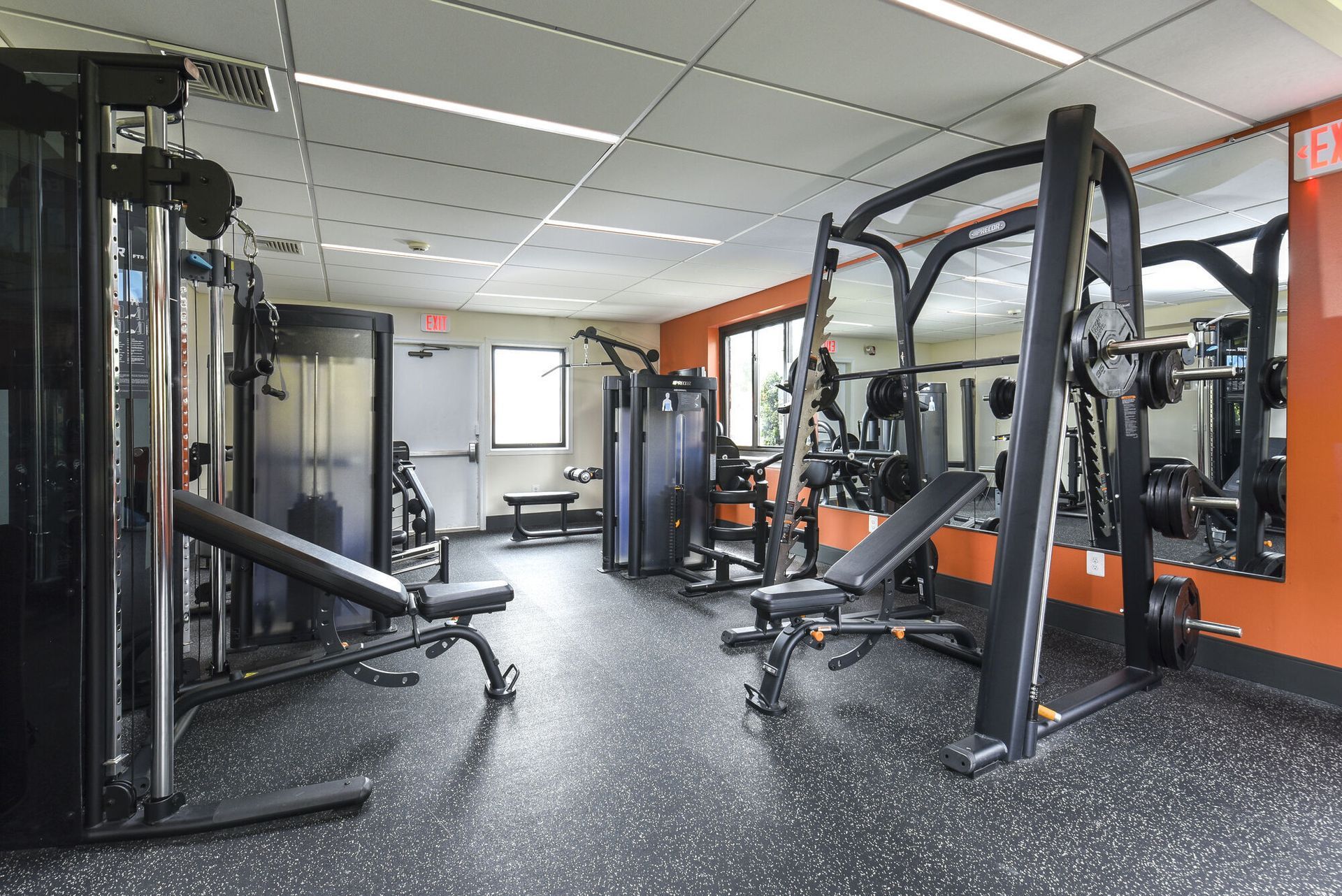 Interior view of a well-equipped apartment community gym with benches and weight machines at The Addison, offers apartments for rent in North Wales, PA.