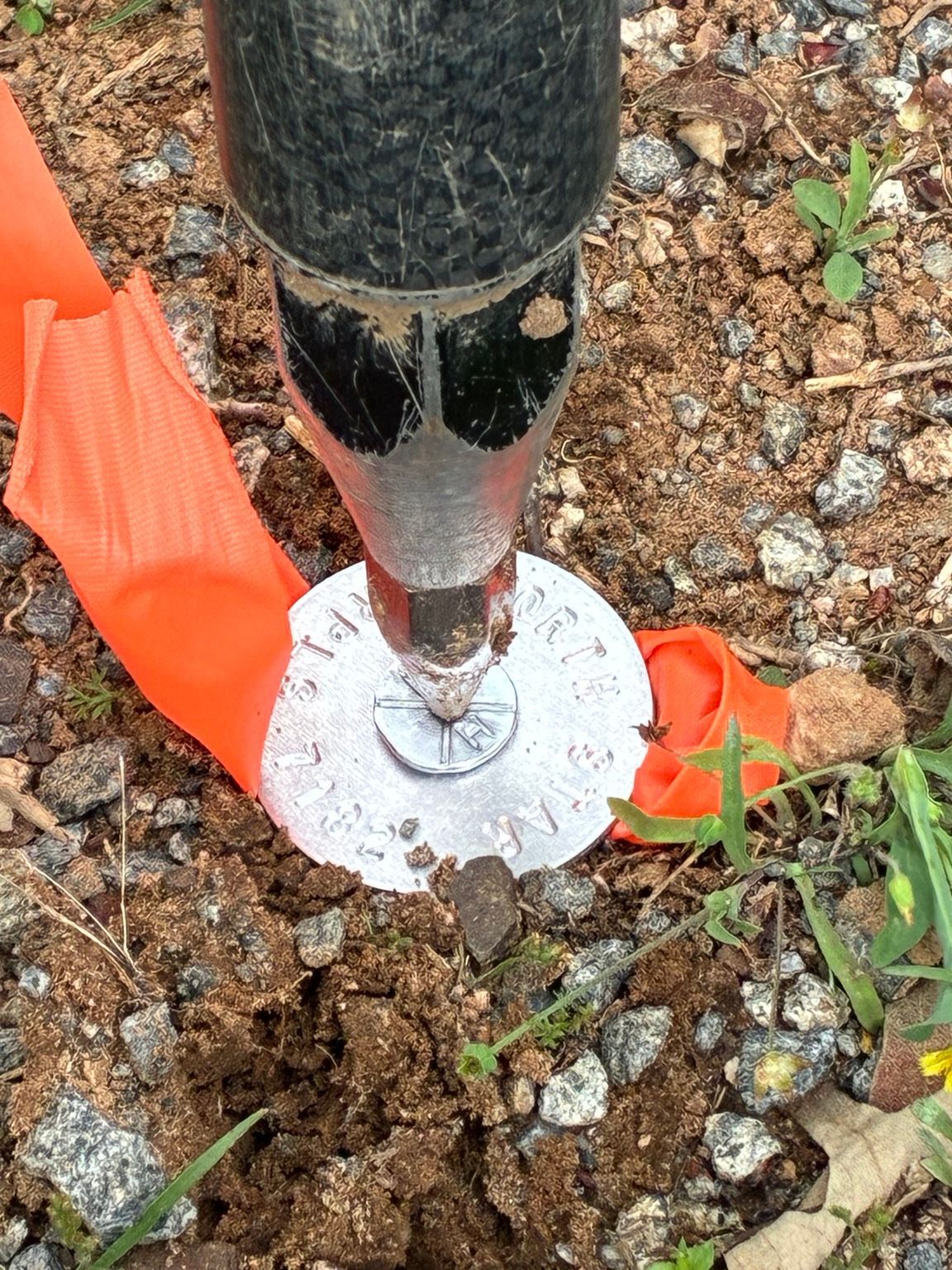 Survey rod positioned over a North Star boundary survey cap