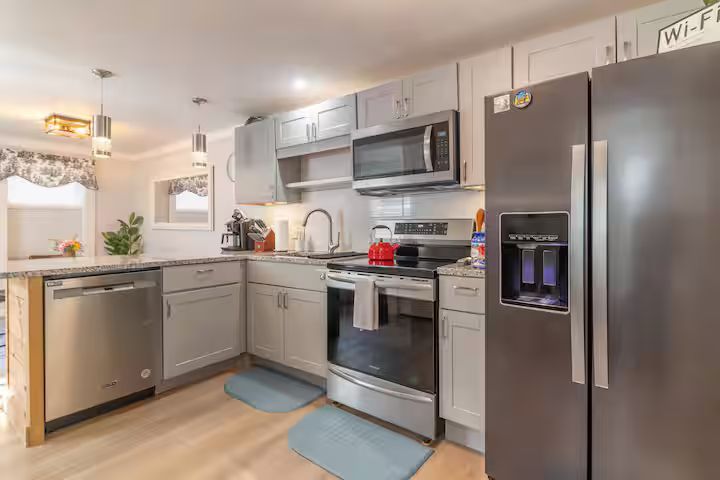 Modern kitchen with stainless steel appliances, gray cabinets, and light wood flooring