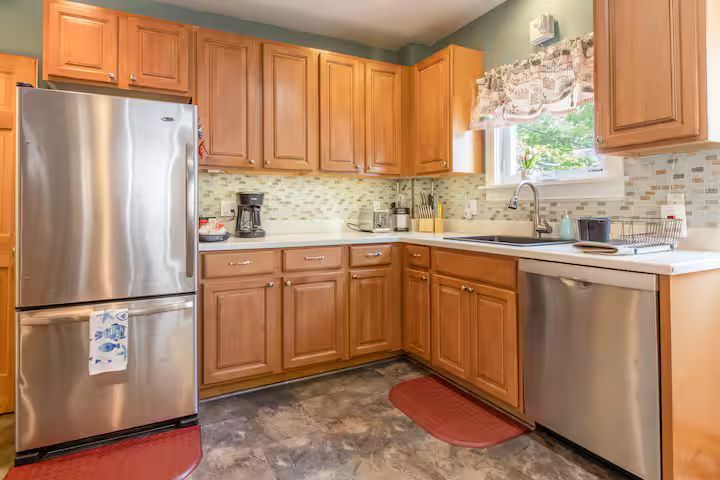 Bright kitchen with wooden cabinets, stainless steel appliances, and a window over the sink.