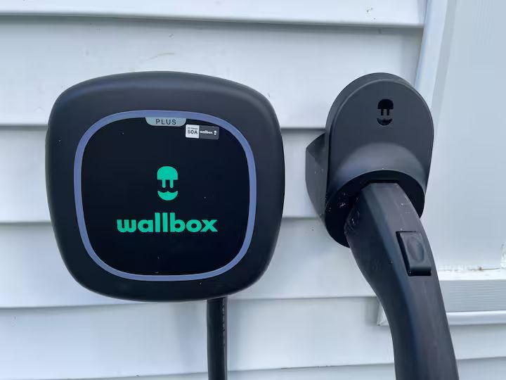Wallbox EV charger mounted on a house exterior, with charging cable plugged in.