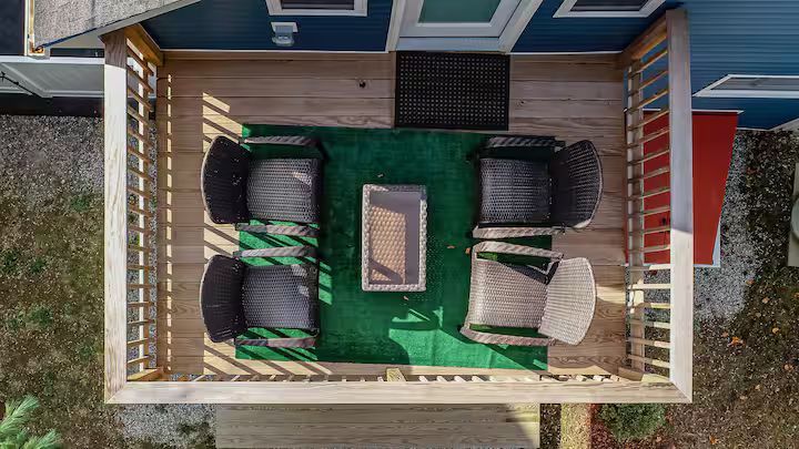 Top-down view of a small patio with green turf, four lounge chairs, and a rectangular fire table.