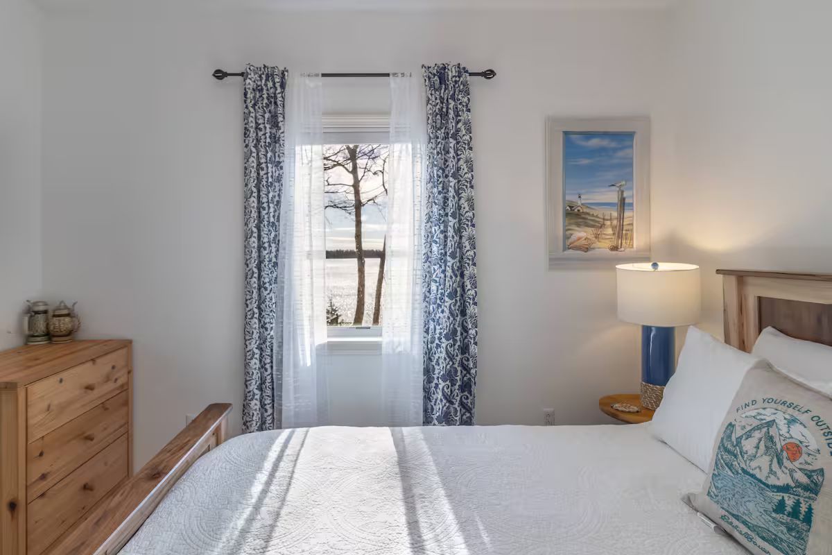 Bright bedroom with bed, dresser, window, and framed wall art