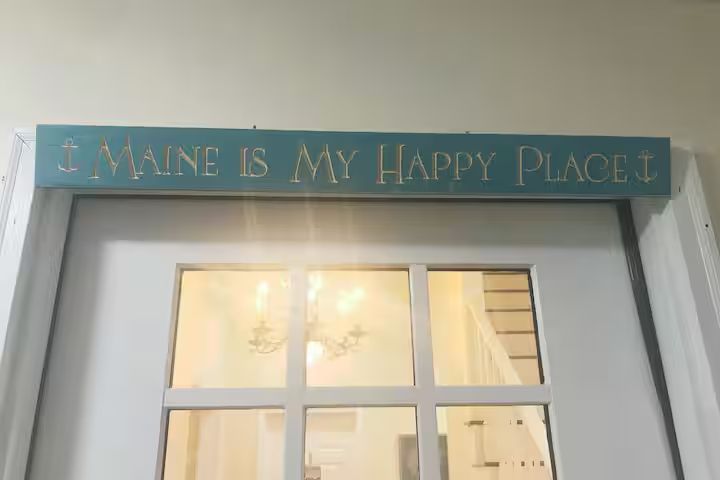 Turquoise sign reading “Maine is my happy place” above a doorway