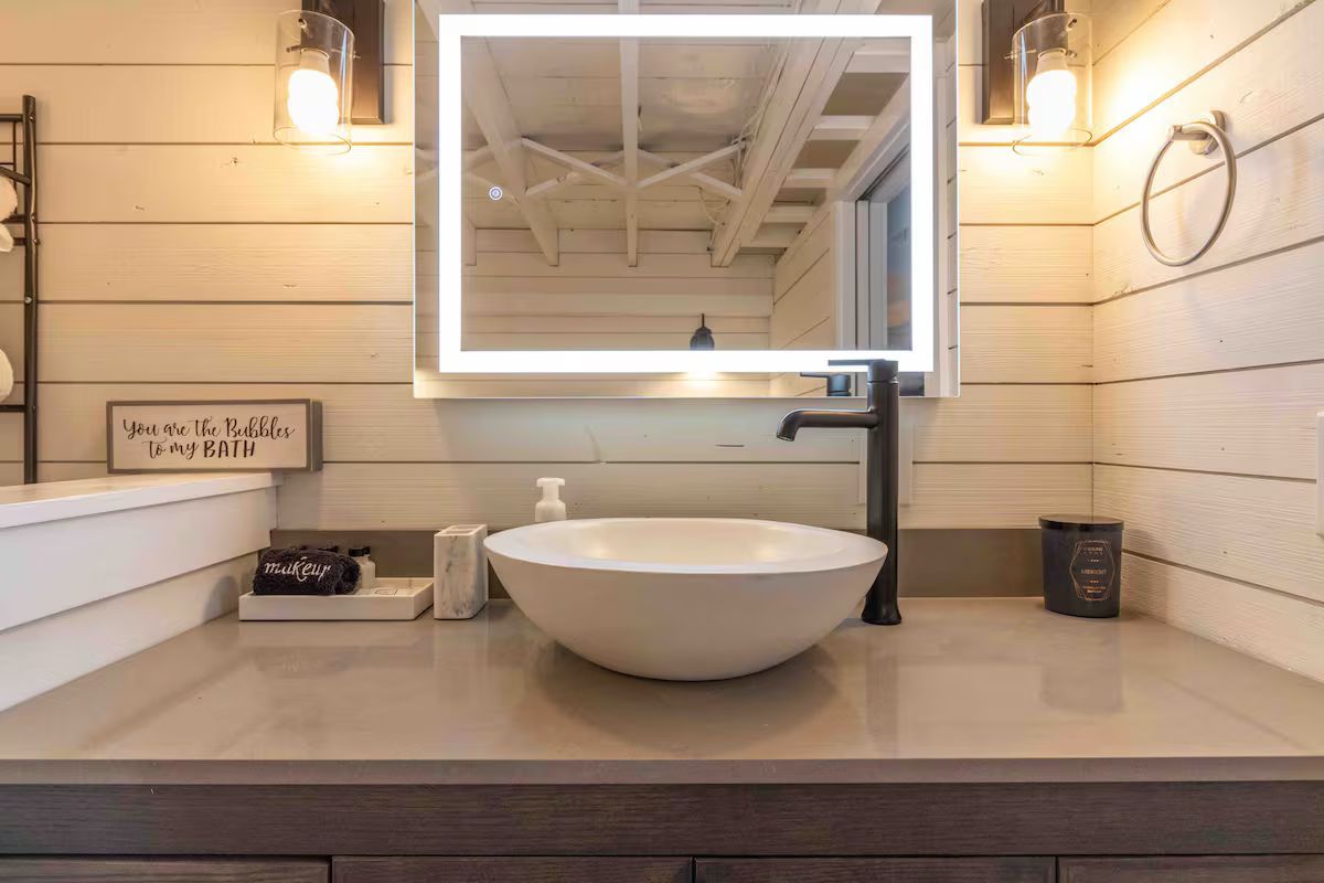 Modern bathroom vanity with round white sink, mirror, and wood-paneled walls
