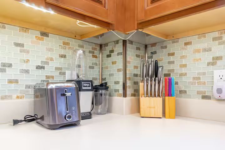 Kitchen counter with toaster, coffee maker, knife block, and tiled backsplash